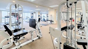 A gym with various exercise machines, a treadmill, and a large window providing natural light. - Great Weekly Rate With Beachfront Views (Panama City Beach)