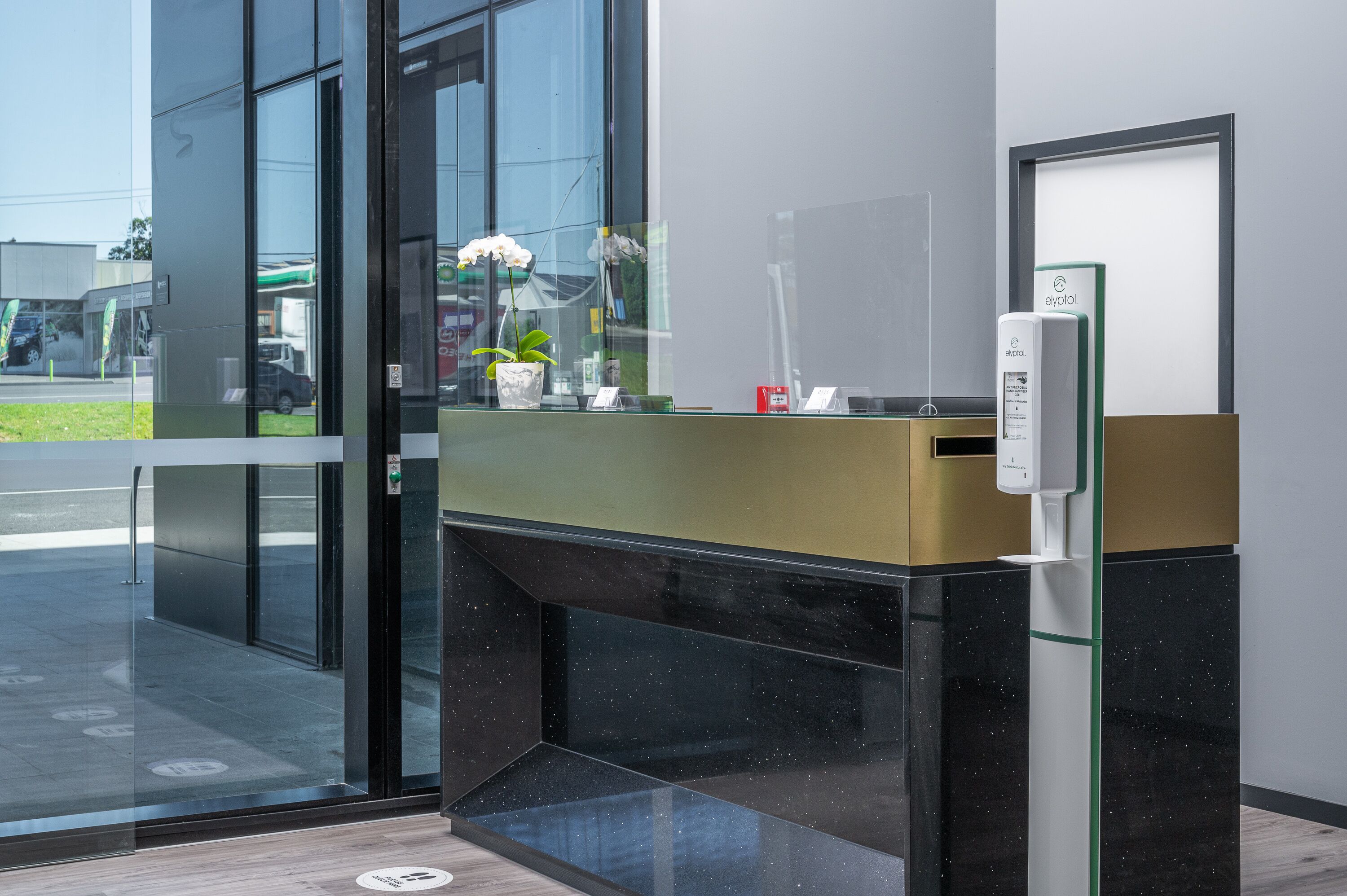 Un comptoir d’accueil moderne avec un séparateur en verre, une plante en pot et une enseigne indiquant « eYpotol ».