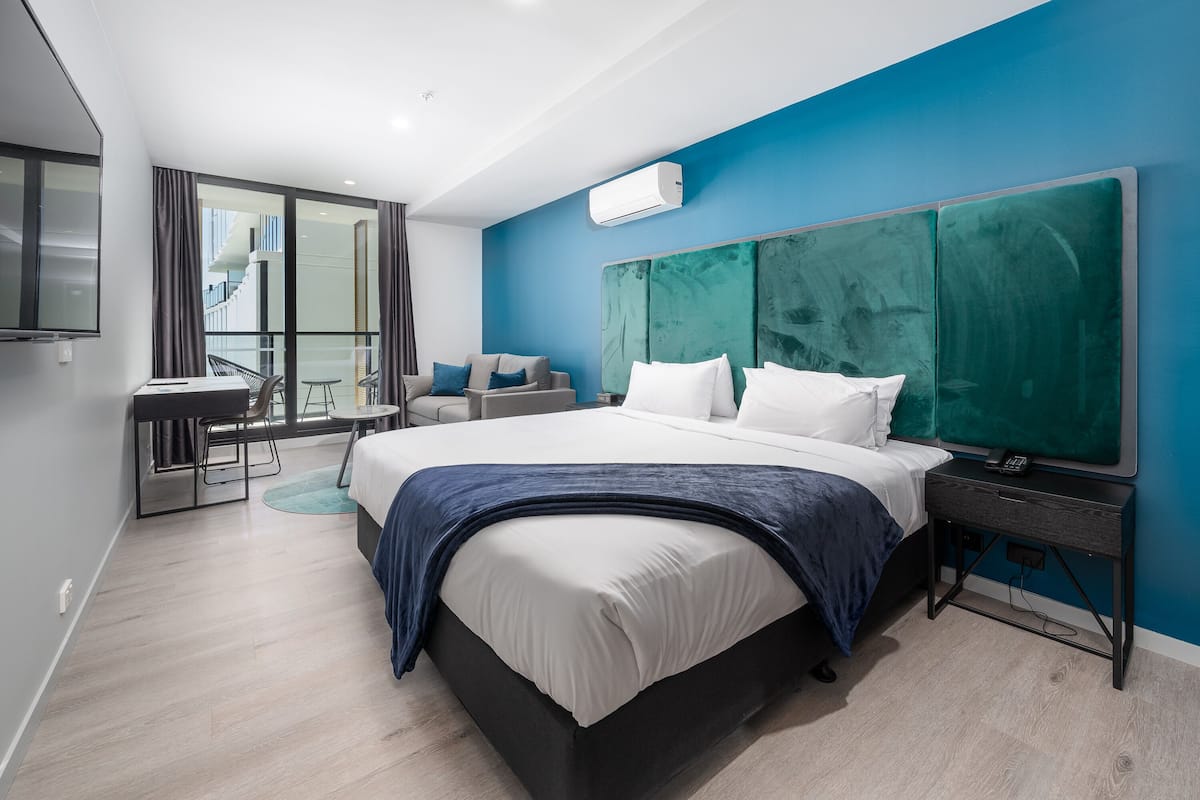 Una camera d'albergo moderna con un grande letto, una scrivania e un balcone con vista.