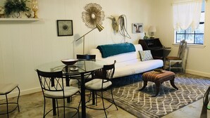 Ein Wohnzimmer mit einem Glastisch, einem weißen Sofa und einem gemusterten Teppich.
