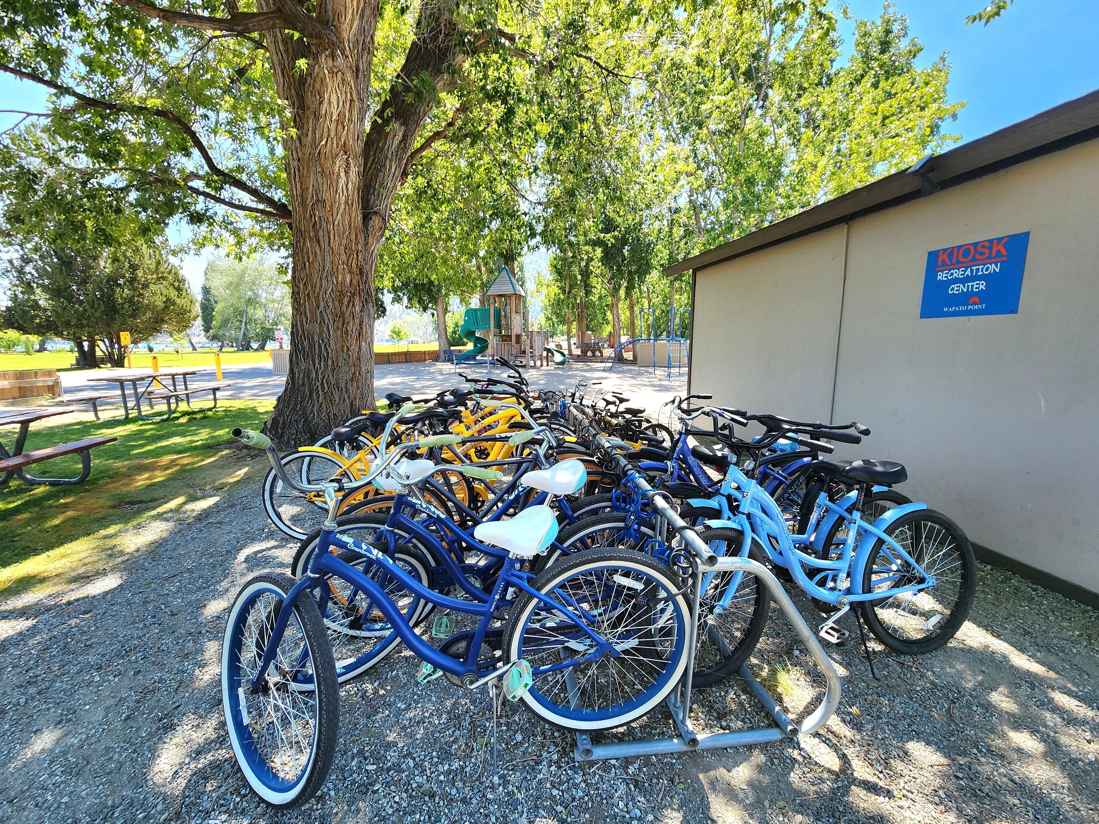 Een fietsenparkeerplaats met meerdere fietsen, een picknicktafel en een bordje voor het Kiosk Recreation Center.