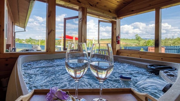 A hot tub with two glasses of water and a tray with flowers. - Smoky Mountain Escape · Mini Golf · Private Hot Tub · Close to Dollywood (Sevierville)
