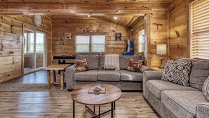 A cozy cabin interior with a wooden interior, a sofa, a coffee table, and a fireplace. - Smoky Mountain Escape · Mini Golf · Private Hot Tub · Close to Dollywood (Sevierville)