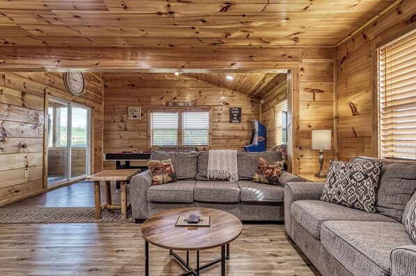 A cozy cabin interior with a wooden interior, a sofa, a coffee table, and a fireplace.