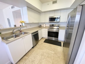 A modern kitchen with white cabinets, stainless steel appliances, and a black rug.