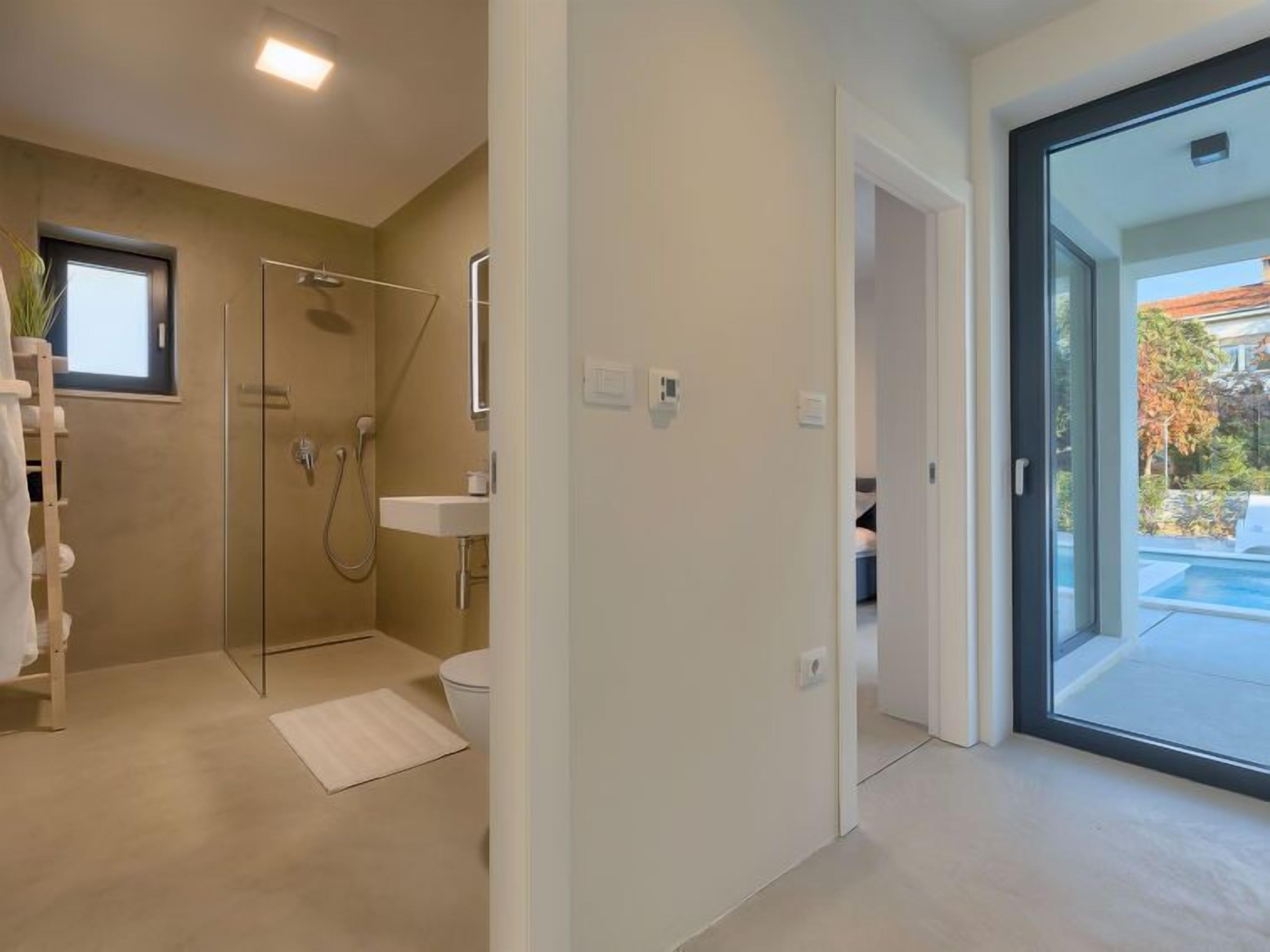 Een moderne badkamer met een douchecabine van glas, een witte wastafel en een toilet.