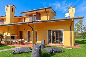 Una casa gialla con un patio, un'antenna parabolica e un camino.