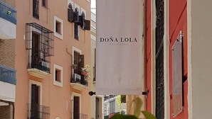 A hotel sign with the name 'DONA LOLA HOTEL' hanging between buildings. - Dona Lola (Seville)