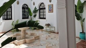 A spacious courtyard with white walls, multiple arches, and tiled flooring. - Dona Lola (Seville)