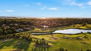 A golf course with sand bunkers, a pond, and a residential area in the background. - Albarella V3 3, Isola di Albarella, Italy (Isola di Albarella)