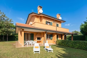 A two-story house with a patio, outdoor seating, and a chimney. - Albarella V3 3, Isola di Albarella, Italy (Isola di Albarella)