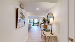 A hallway with a wooden bench, a mirror, and a vase with flowers. - Large Three Bedroom Villa Overlooking the George Fazio Golf Course! (Hilton Head)