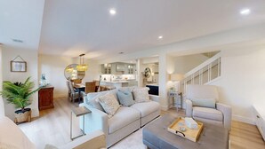A spacious living room with a sofa, coffee table, and a dining area with chairs and a table. - Large Three Bedroom Villa Overlooking the George Fazio Golf Course! (Hilton Head)