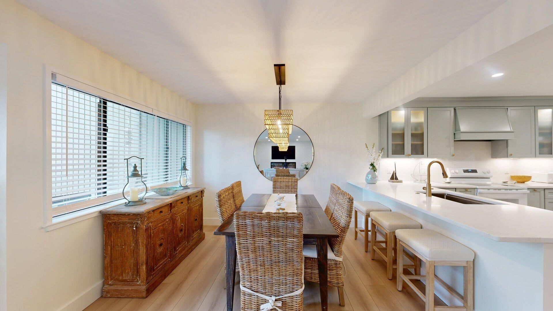 Une cuisine moderne avec un coin repas, comprenant un îlot central, des meubles en bois et un grand miroir.