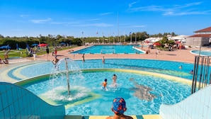 Zona de piscina con varias piscinas, un tobogán acuático y una zona de estar techada.