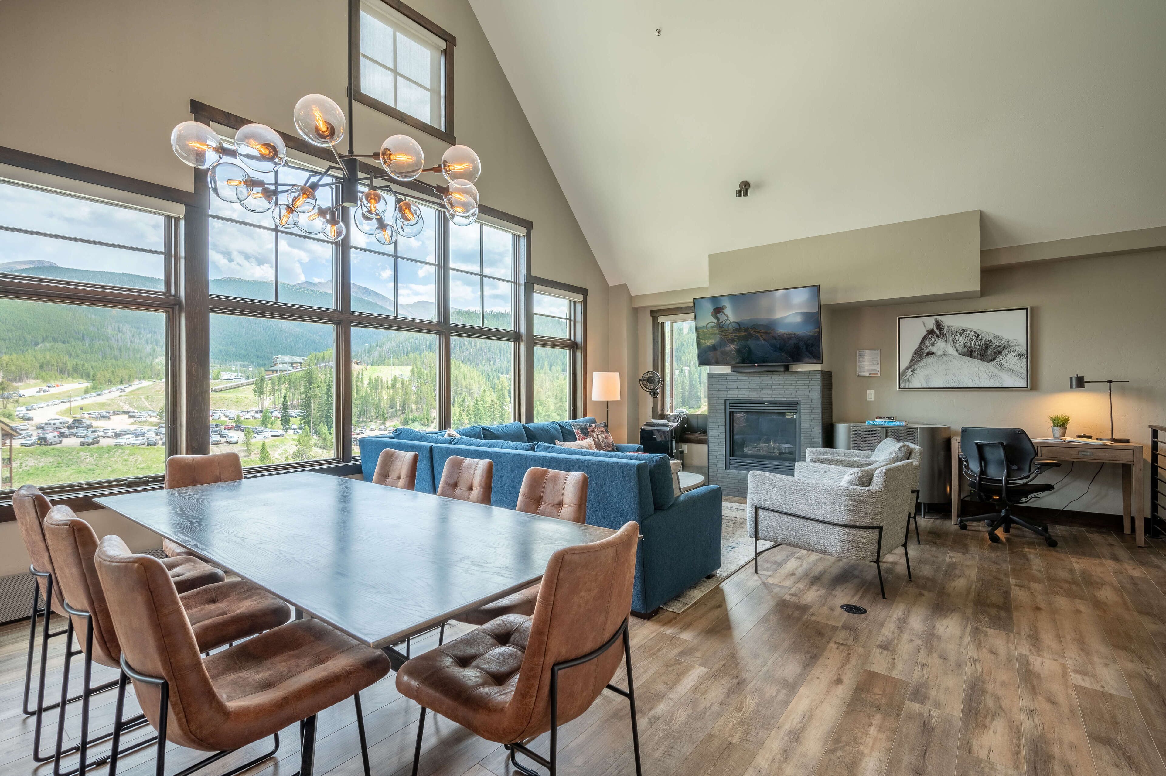 A spacious living area with a large dining table, blue sofa, and a fireplace.