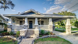 A two-story house with a covered porch, stone pillars, and a brick pathway leading to the entrance. - Historic Home Steps from Lake Hollingsworth, (Lakeland)