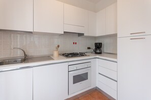 A modern kitchen with white cabinets, a stainless steel sink, a gas stove, and a coffee maker. - Albarella V4P, Isola di Albarella, Italy (Isola di Albarella)