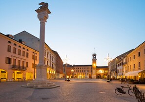 A historic square with a central monument, cobblestone pavement, and surrounding buildings with balconies and awnings. - Albarella V4P, Isola di Albarella, Italy (Isola di Albarella)