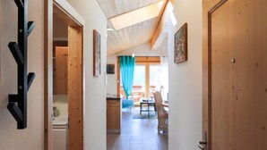 A hallway with wooden doors, a kitchen area, and a dining space with a table and chairs.