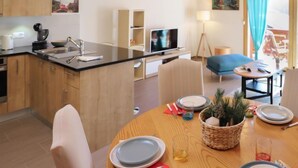 A modern kitchen with wooden cabinets, a built-in oven, and a dining area with a round table set for two.