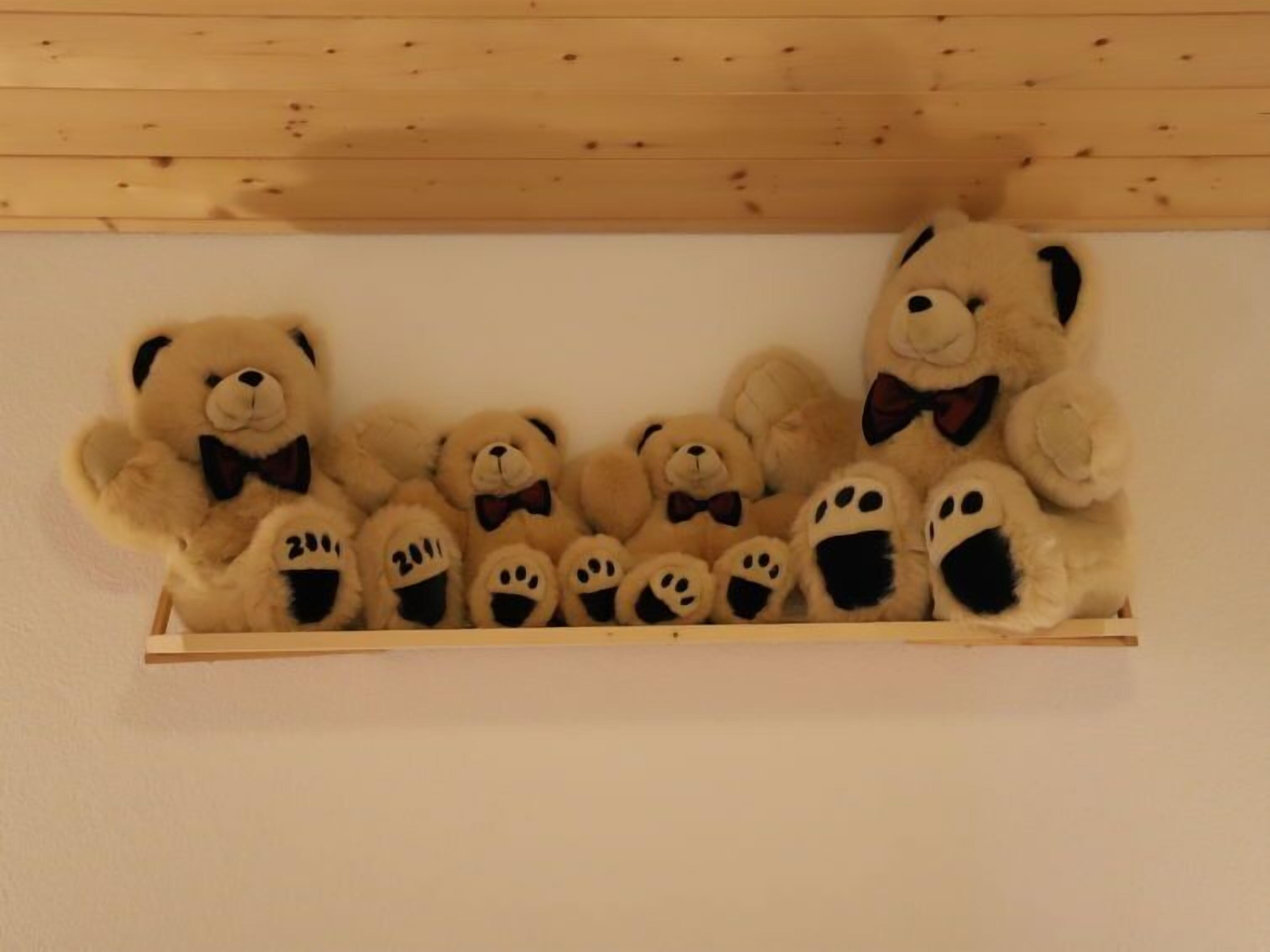 A wooden shelf with a row of teddy bears and a panda bear.