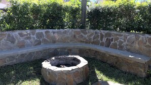 Un hogar de piedra rodeado por un muro de piedra curvo, con dos troncos de madera cerca.