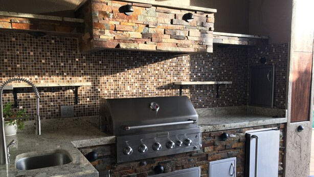 Cocina exterior con una parrilla integrada, un lavaplatos y armarios de almacenamiento.