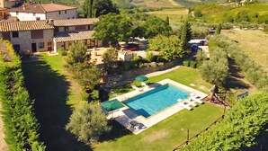 Una villa con piscina, rodeada de exuberante vegetación y vistas panorámicas al campo.