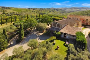 Una villa con patio, rodeada de viñedos y cipreses.