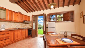 Una cocina con armarios de madera, una mesa de comedor preparada para dos personas y vistas al exterior.