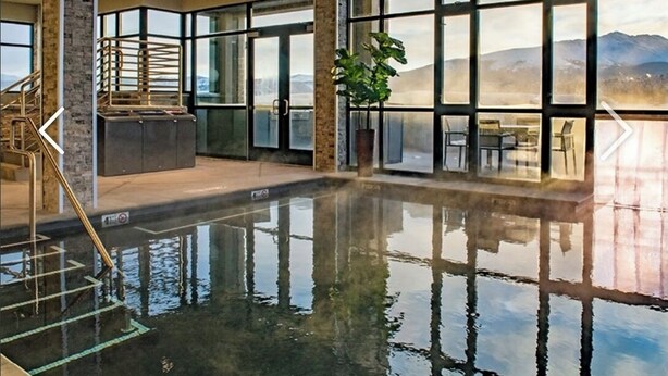 Una piscina interior con vistas despejadas a montañas a través de amplios ventanales.