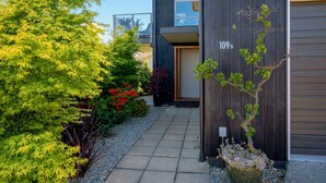 A modern building with a dark exterior, a visible entrance, and a pathway leading to the entrance. - Kings View - Wanaka Holiday Home (Wanaka)