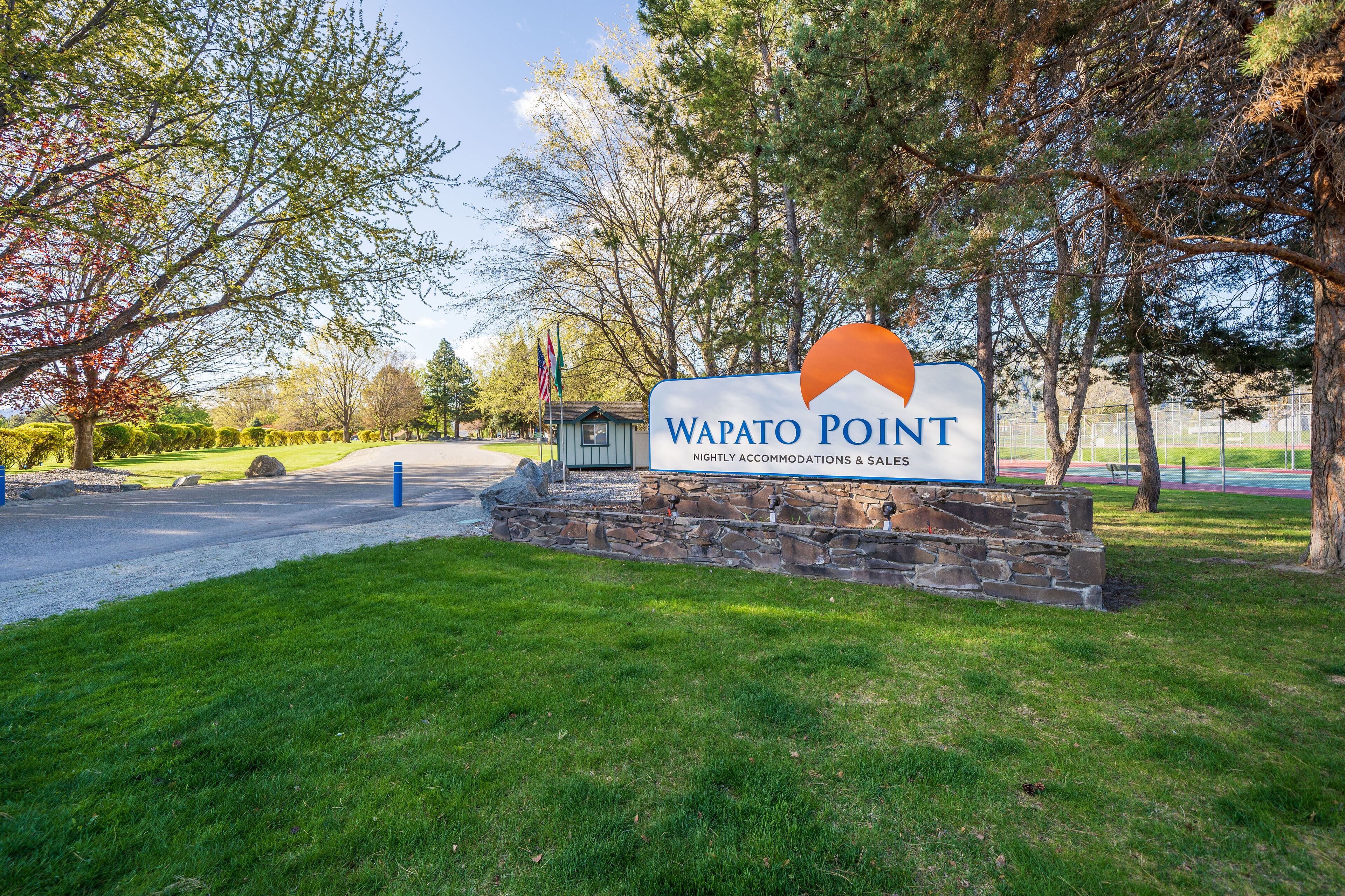 A sign for Wapato Point with a stone base and a blue border.