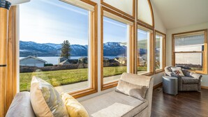 Un salón acogedor con un ventanal que ofrece vistas a montañas y un lago.