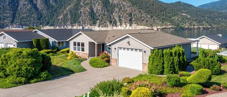 A residential area with houses, well-maintained lawns, and a lake in the background.