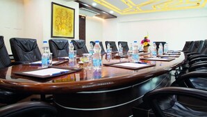 A conference room with a long table, black leather chairs, water bottles, and a framed artwork on the wall. - Ramyas Hotels (Tiruchirappalli)