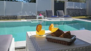 Area piscina con lettini, un tavolo con bevande e pane, e una vista libera sulla piscina.
