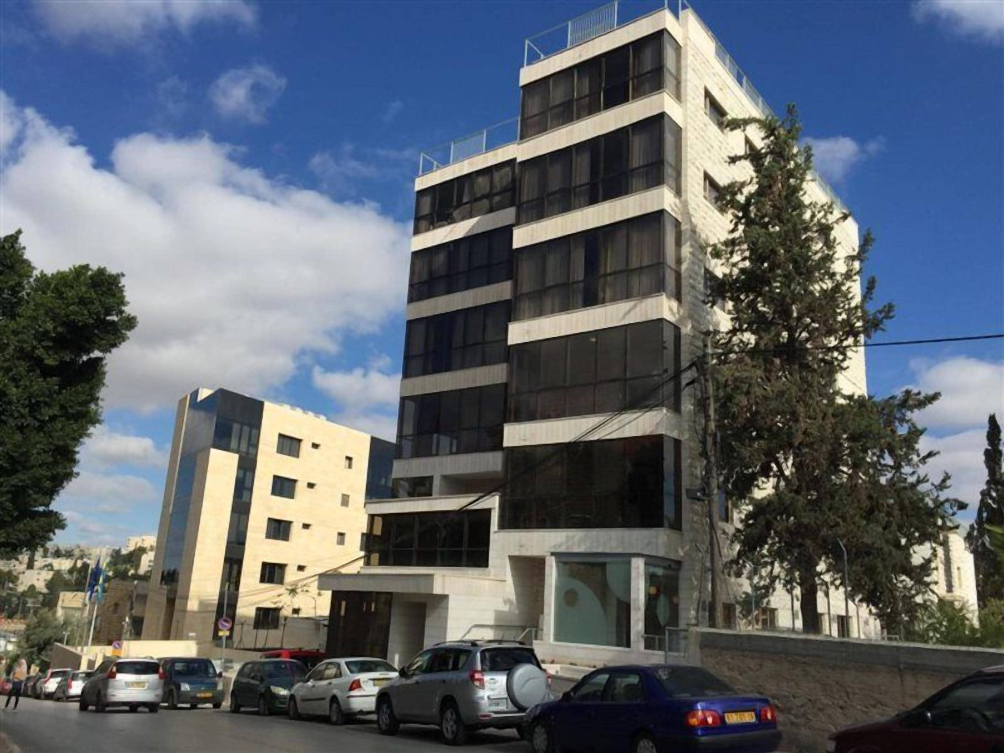 Un edificio de varios pisos con un diseño arquitectónico moderno, que combina fachadas de vidrio y concreto.