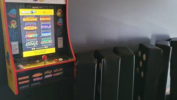 A Pac-Man arcade game, a framed picture of cows, and black chairs.