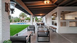 An outdoor patio with seating, a pool, and a kitchen visible through the windows. - Elegance & Class - Centrally located Scottsdale home with heated* pool & fire-pit (Scottsdale)