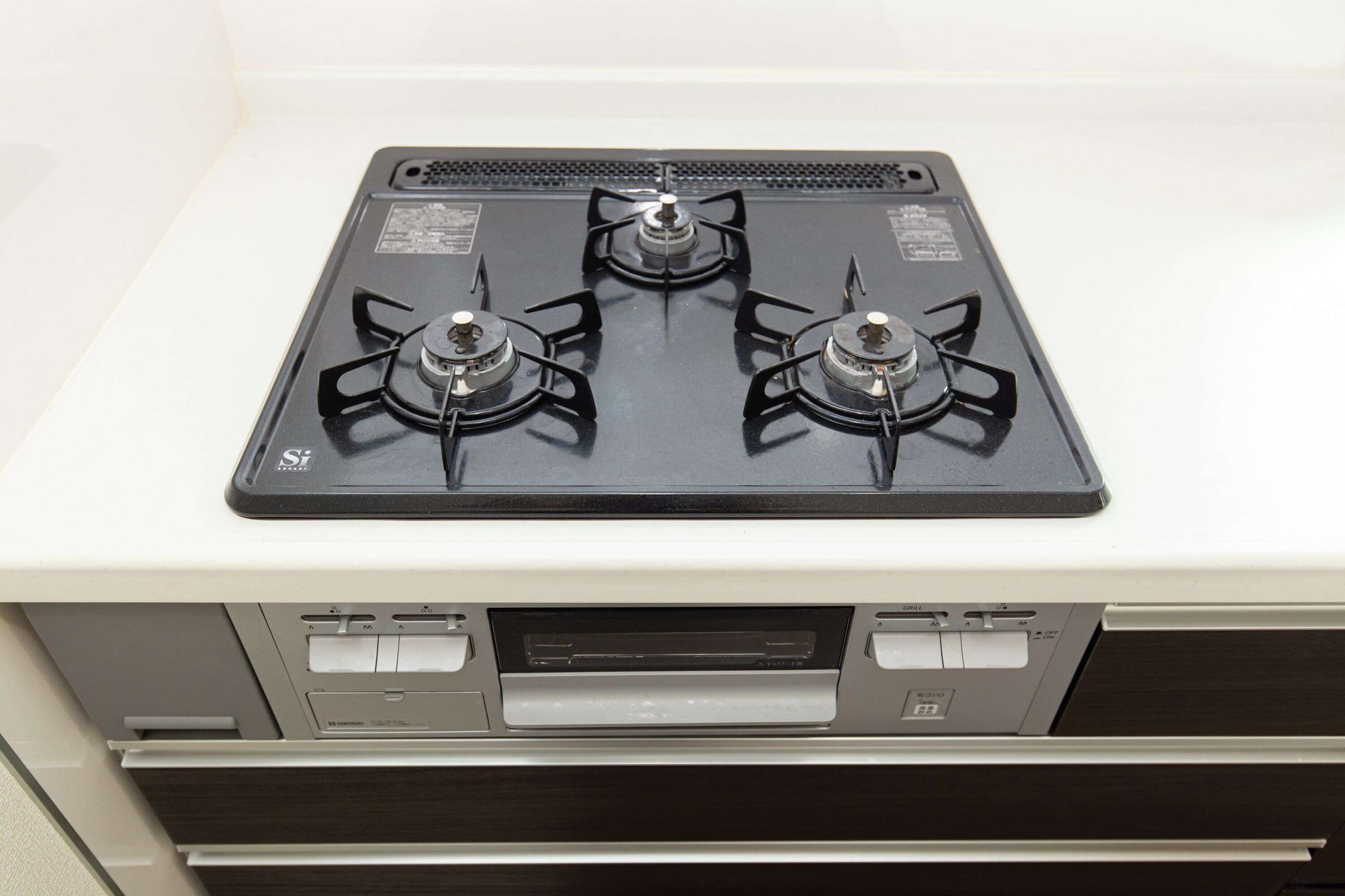 A kitchen with a three-burner gas stove and a built-in oven.