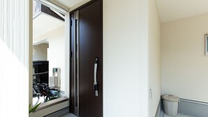 Ein moderner Hauseingang einer Wohnung mit einer Schiebetür, einem kleinen Mülleimer und einem Fahrrad davor.