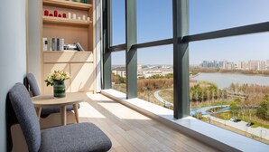 Ein modernes Zimmer mit einem großen Fenster, einem Holzregal und einem Tisch mit Stühlen.