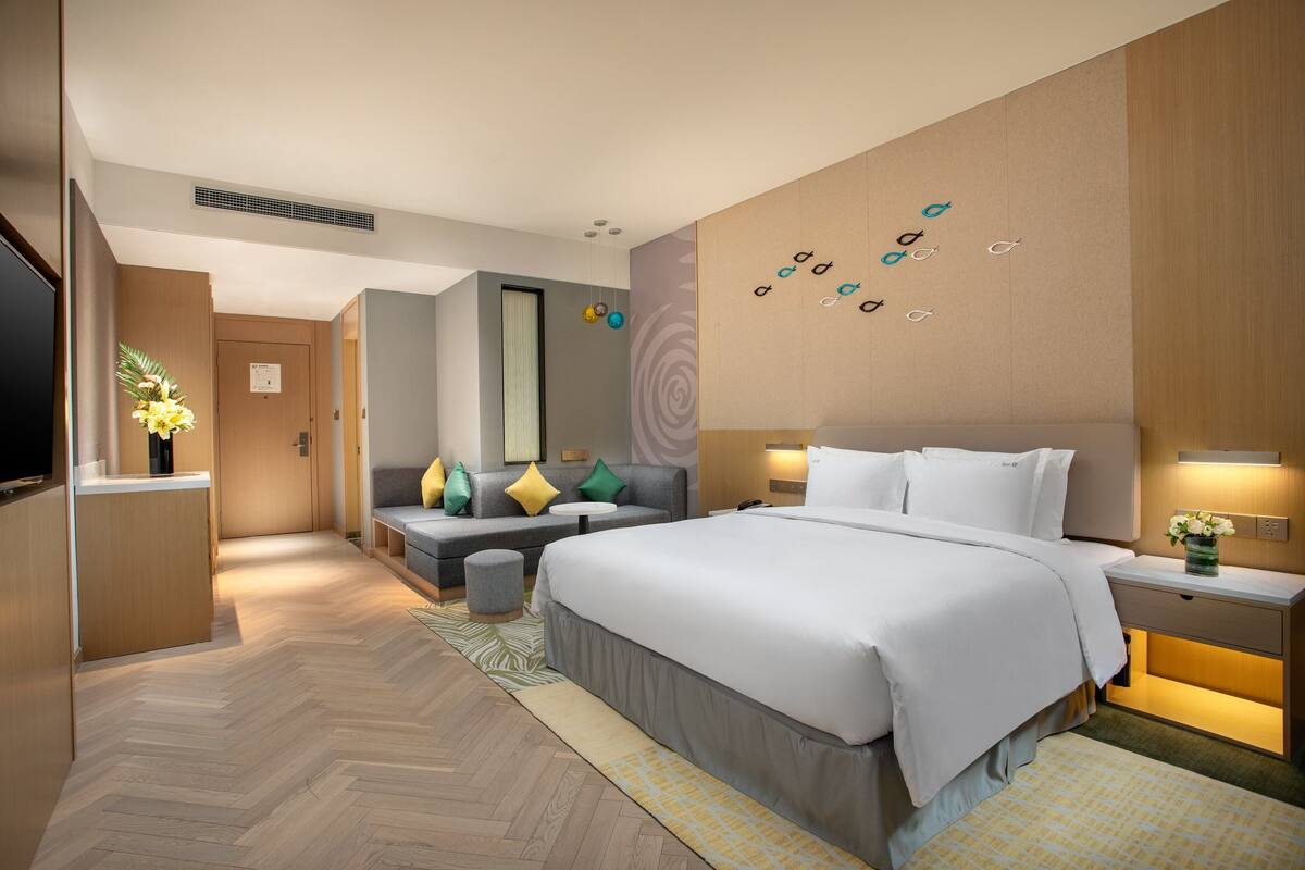 Ett modernt hotellrum med en stor säng, en soffa, ett skrivbord och en TV.