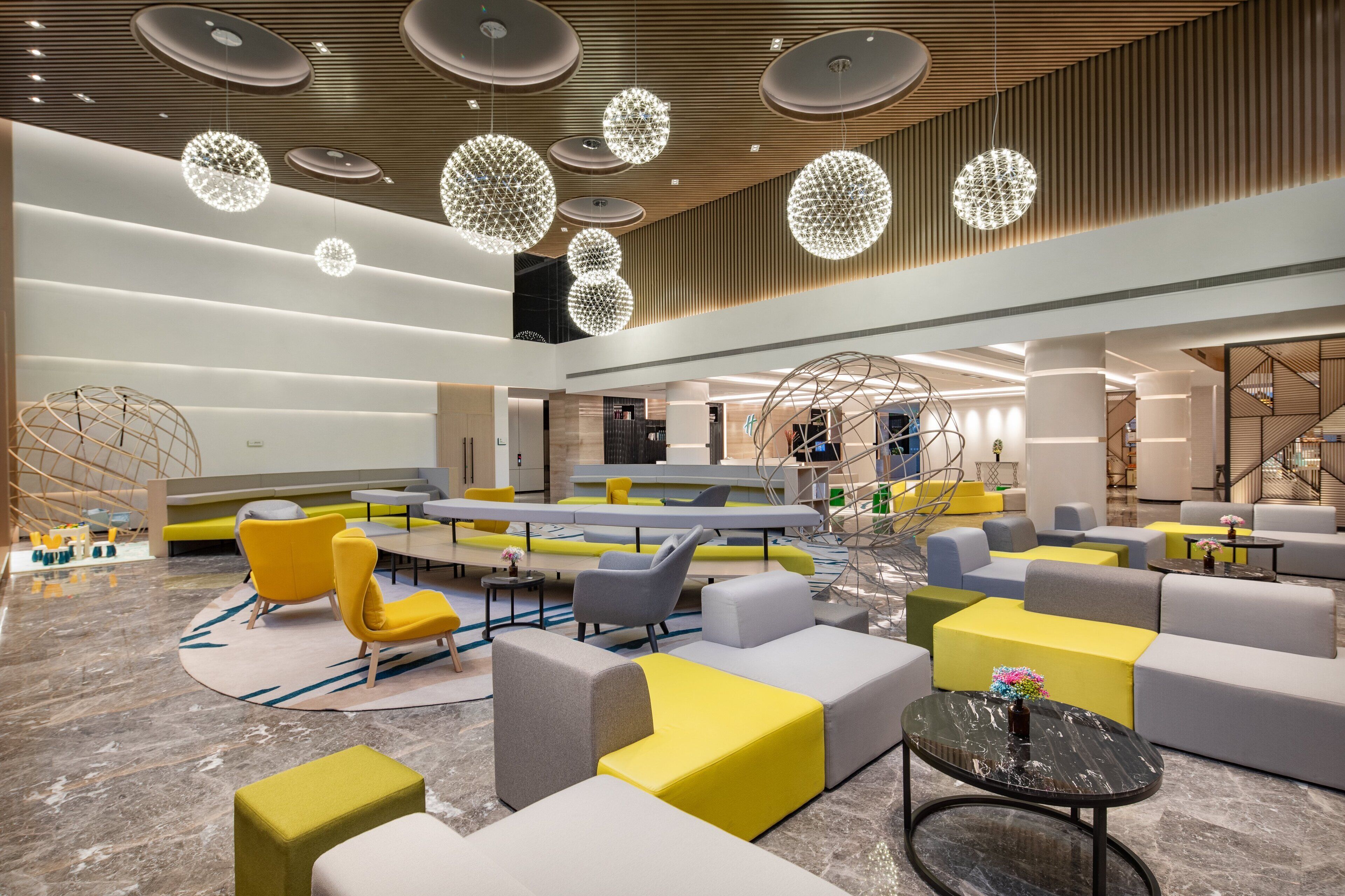 Eine moderne Lobby mit Sitzbereichen, einer Treppe und einem großen Bildschirm.