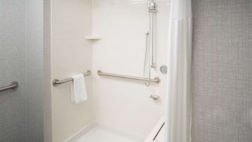 A walk-in shower with a handrail, a towel rack, and a showerhead.