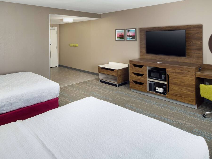 Ein Hotelzimmer mit zwei Betten, einem Fernseher, einem Schreibtisch und einem Sessel.