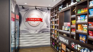 A snack aisle with a variety of packaged goods and a 'Treats' sign on the wall. - Hampton Inn Kissimmee North (Kissimmee)