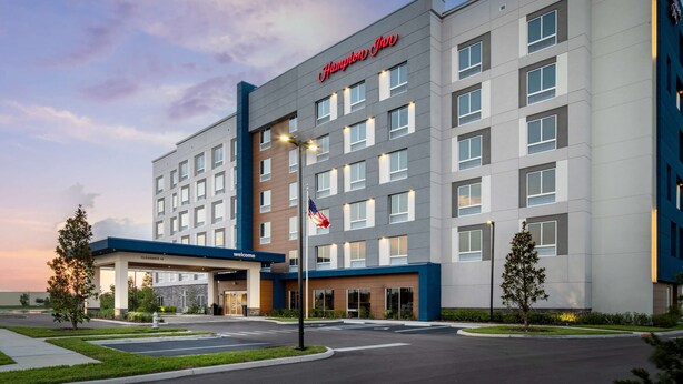 A Hampton Inn hotel with a modern design, featuring a clear entrance, a flag, and a well-lit exterior. - Hampton Inn Kissimmee North (Kissimmee)